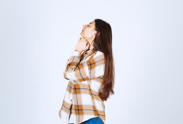 modelo de chica joven de pie sobre la pared blanco-gris.