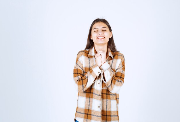 modelo de chica joven de pie sobre la pared blanco-gris.