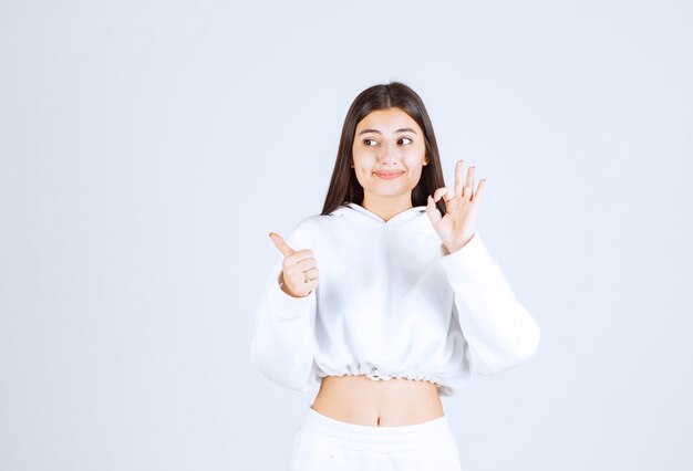 modelo de chica joven positiva que muestra un gesto aceptable y un pulgar hacia arriba.