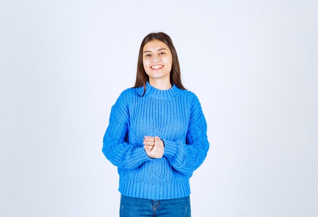 modelo de chica joven en suéter azul de pie y posando en blanco-gris.