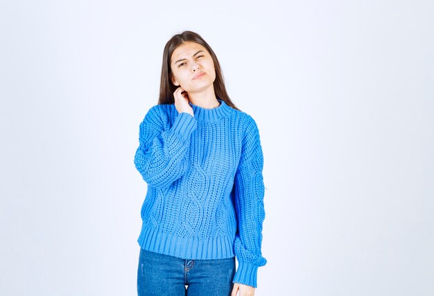 modelo de chica joven en suéter azul de pie y posando en blanco-gris.