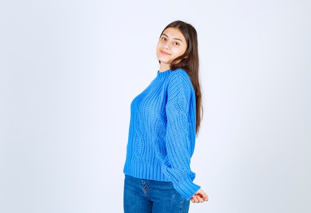 modelo de chica joven en suéter azul de pie y posando en blanco-gris.