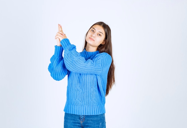 modelo de chica joven en suéter azul de pie y posando en blanco-gris.