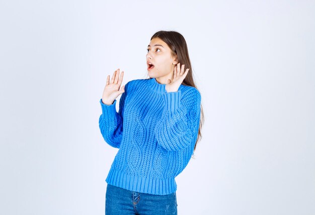 modelo de chica sorprendida en suéter azul levantando las manos.