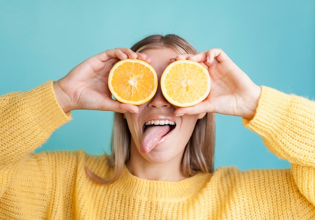 Foto gratuita modelo divertido que cubre los ojos con naranjas
