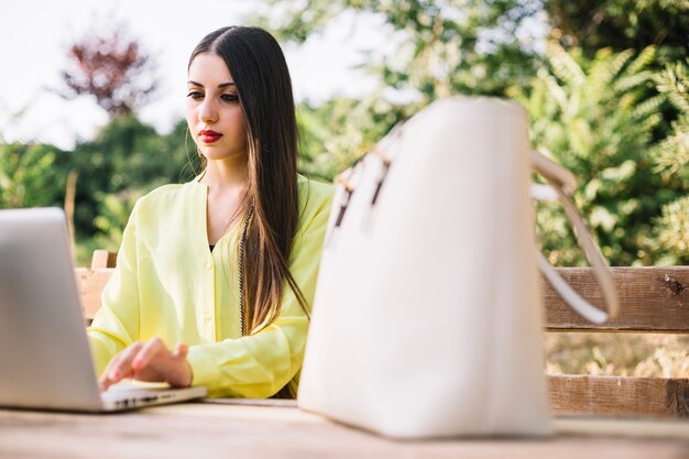 Modelo elegante con la computadora portátil en el parque