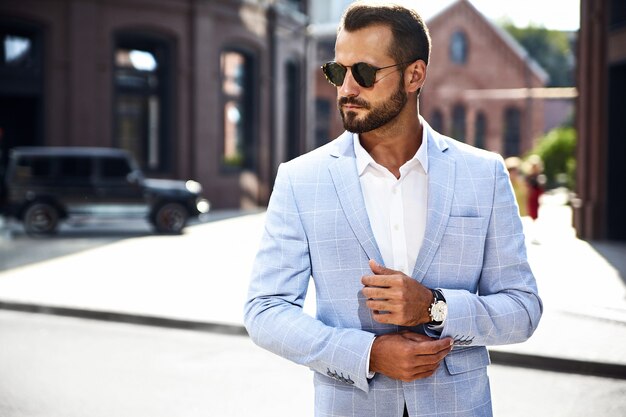 modelo de empresario de moda guapo vestido con elegante traje azul posando en la calle