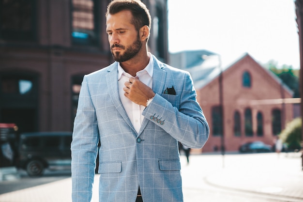 modelo de empresario de moda guapo vestido con elegante traje azul posando en la calle