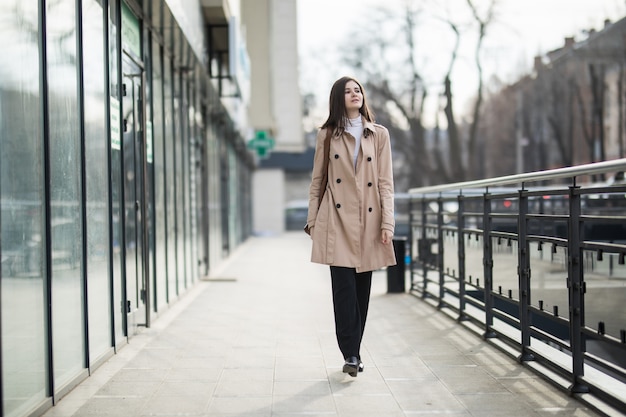 Modelo femenino de cabello castaño caminando por la calle en ropa casual