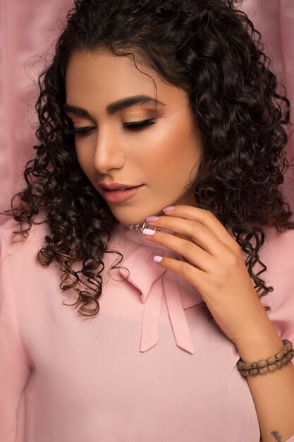 Modelo femenino en camisa casual rosa y maquillaje ligero