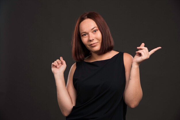 Modelo femenino en camisa negra apuntando a algo.