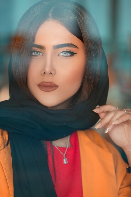 Modelo femenino en hijab negro y chaqueta naranja