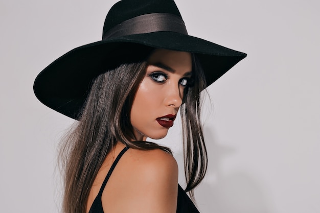 Foto gratuita modelo femenino increíble con estilo eficaz en traje de halloween de bruja negra que se prepara para la fiesta sobre una pared blanca aislada