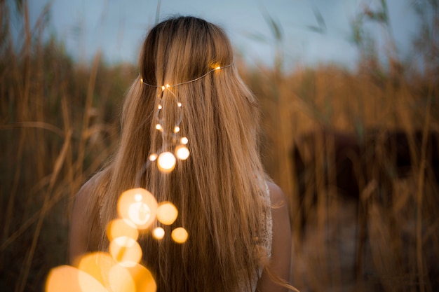 Modelo femenino con perlas de iluminación en la naturaleza