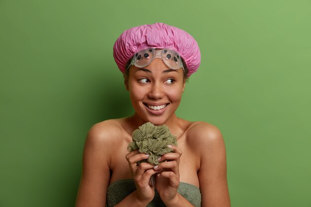 Modelo femenino sonriente saludable envuelto en una toalla de baño