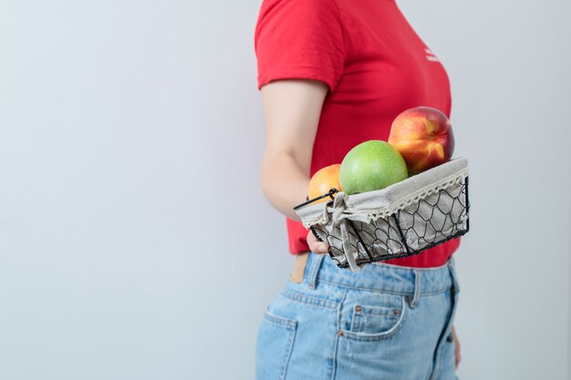 Foto gratuita modelo femenino sosteniendo una canasta de frutas