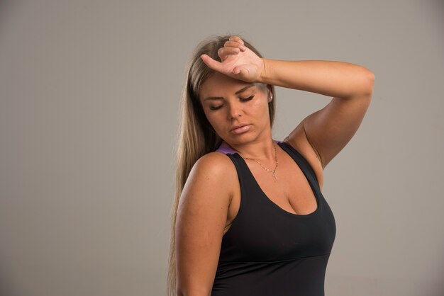 Modelo femenino en sujetador deportivo sostiene su cabeza.