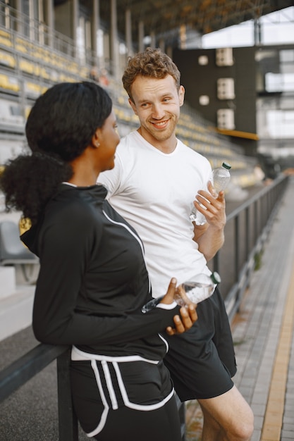 Modelo de fitness afroamericano y hombre caucásico hablando mientras entrena al aire libre