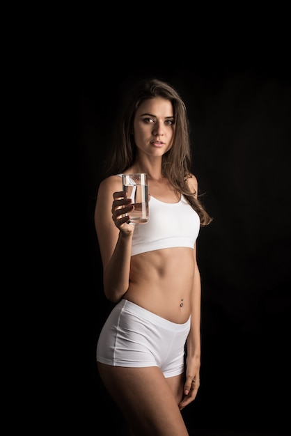 Modelo de fitness femenino sosteniendo un vaso de agua