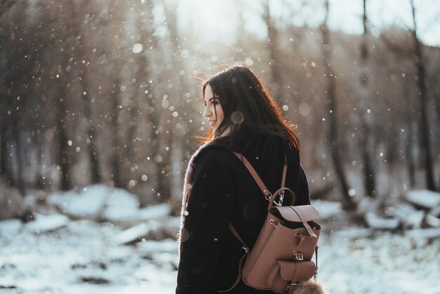 Modelo hermoso joven que presenta en bosque del invierno. elegante retrato de moda