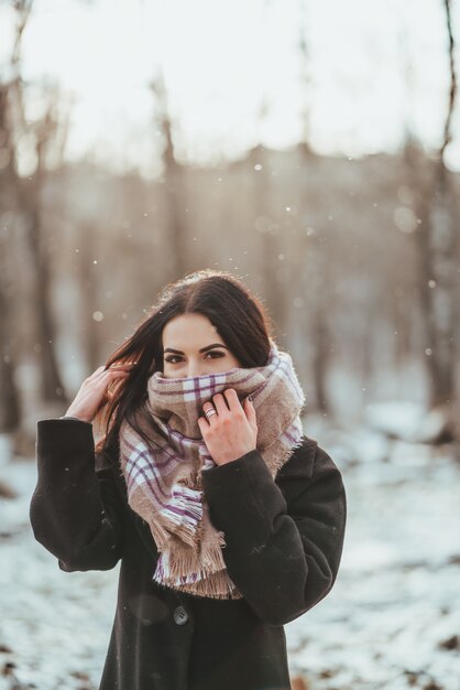 Modelo hermoso joven que presenta en bosque del invierno. elegante retrato de moda