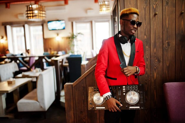 Modelo de hombre afroamericano de moda DJ en traje rojo con controlador de dj