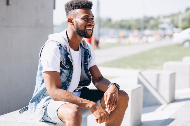 Modelo del hombre afroamericano que se sienta en parque en el fondo blanco