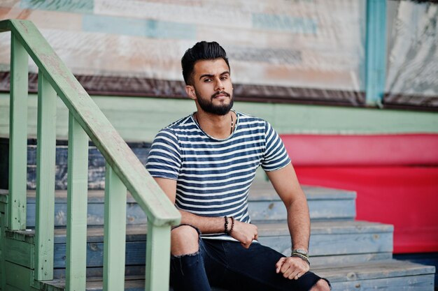 Modelo de hombre de barba árabe alto guapo en camisa despojada posó al aire libre