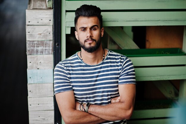 Modelo de hombre de barba árabe alto guapo en camisa despojada posó al aire libre