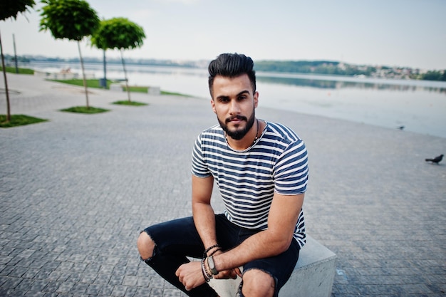 Modelo de hombre de barba árabe alto guapo en camisa despojada posó al aire libre