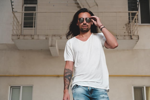 Modelo de hombre barbudo elegante posando con gafas de sol