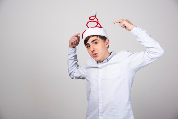 Modelo de hombre joven de pie y apuntando al sombrero de Navidad