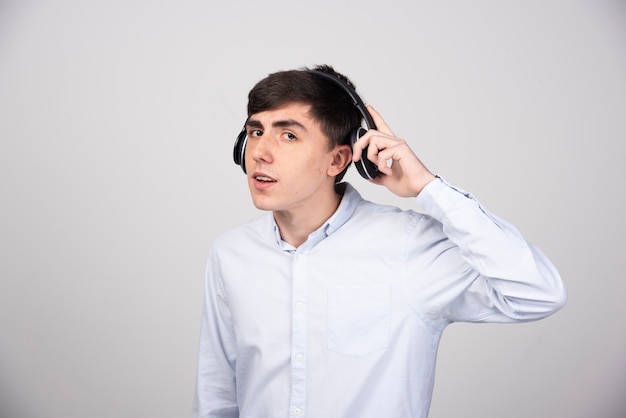 Modelo de hombre joven de pie con auriculares y mirando a la cámara