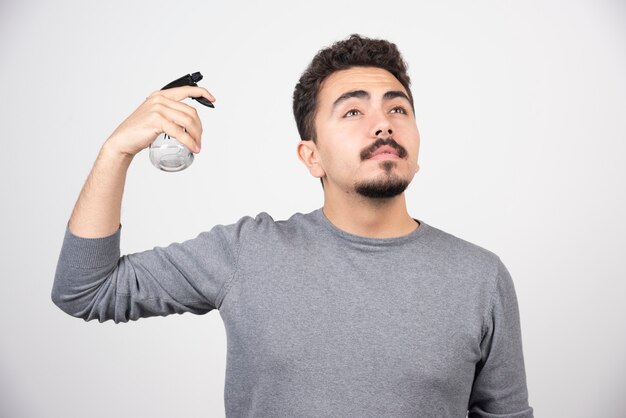 Un modelo de hombre joven sosteniendo una botella de spray de plástico.