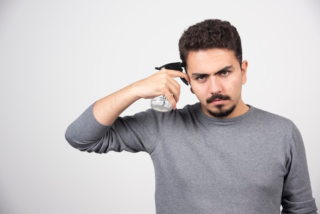 Un modelo de hombre joven sosteniendo una botella de spray de plástico.