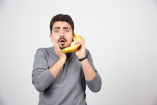 Un modelo de hombre joven sosteniendo un plátano como teléfono.