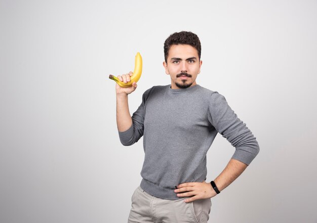 Un modelo de hombre joven sosteniendo un plátano.