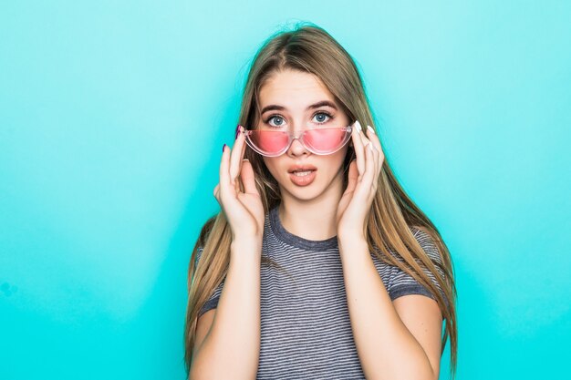 Modelo joven bastante sorprendido en camiseta de moda, sombrero y gafas transparentes aisladas sobre fondo verde