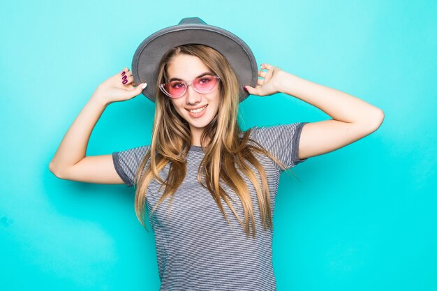 Modelo joven muy sonriente en camiseta de moda, sombrero y gafas transparentes aisladas sobre fondo verde