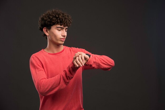 Modelo joven con pelos rizados comprobando su tiempo.