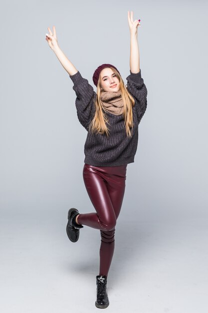 Modelo joven sonriente muy feliz en suéter oscuro de ropa casual de moda en blanco con sombras