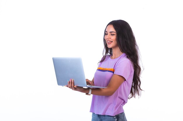 Modelo joven sosteniendo una computadora portátil plateada y con videollamada.