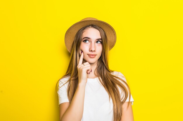 Modelo lindo en camiseta blanca y sombrero entre fondo naranja con cara divertida