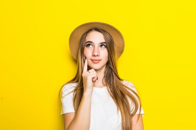 Modelo lindo en camiseta blanca y sombrero entre fondo naranja con cara divertida