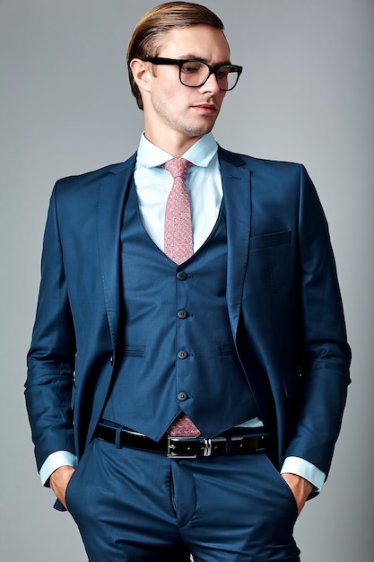 Foto gratuita modelo masculino elegante elegante joven del hombre de negocios en traje azul y gafas de moda, posando en estudio