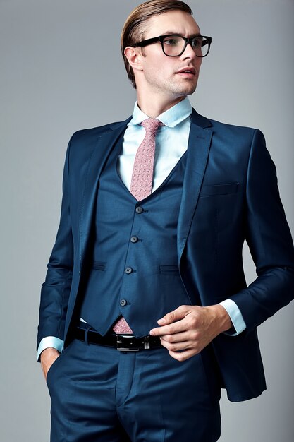 Modelo masculino elegante elegante joven del hombre de negocios en traje azul y gafas de moda, posando en estudio