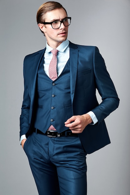 Modelo masculino elegante elegante joven del hombre de negocios en traje azul y gafas de moda, posando en estudio