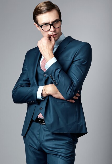 Modelo masculino elegante elegante joven del hombre de negocios en traje azul y gafas de moda, posando en estudio