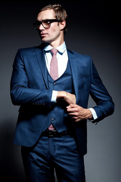 Modelo masculino elegante elegante joven del hombre de negocios en traje azul y gafas de moda, posando en estudio