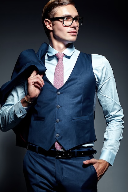 Modelo masculino elegante elegante joven del hombre de negocios en traje azul y gafas de moda, posando en estudio